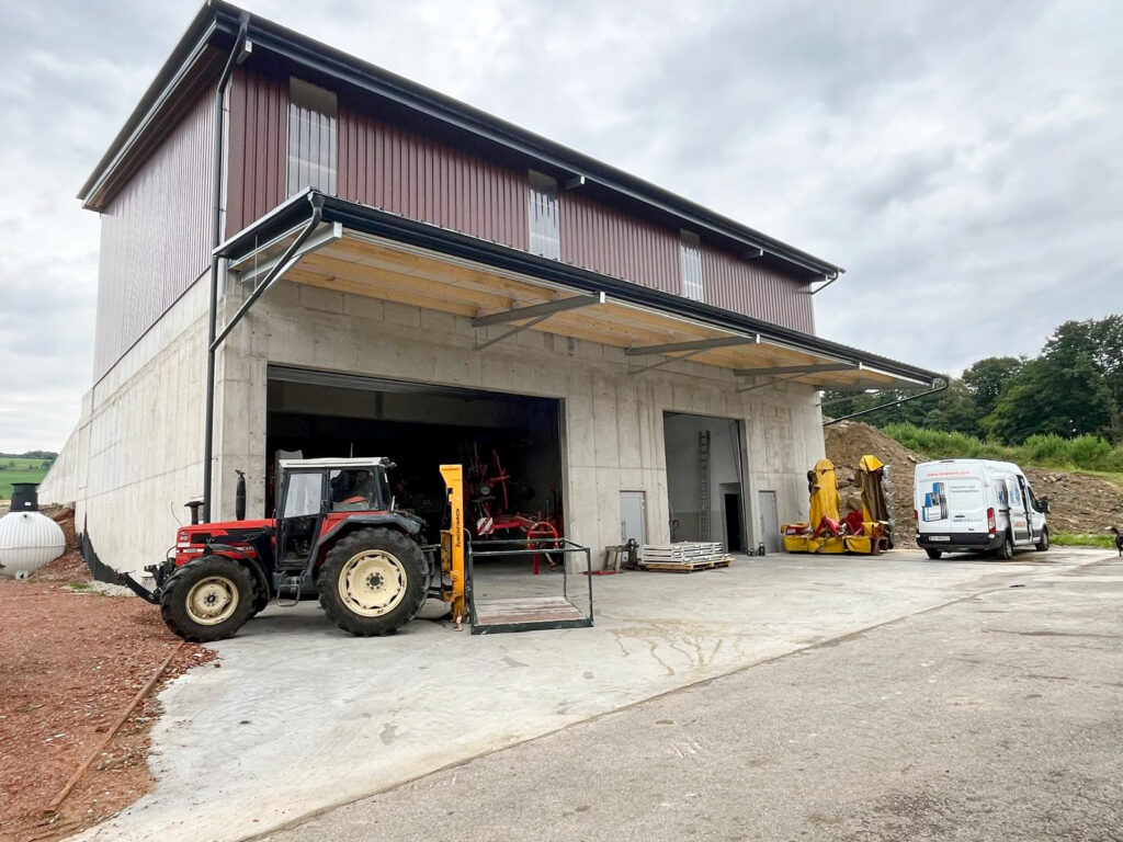 Traktor steht vor Maschinenhalle einer Landwirtschaft